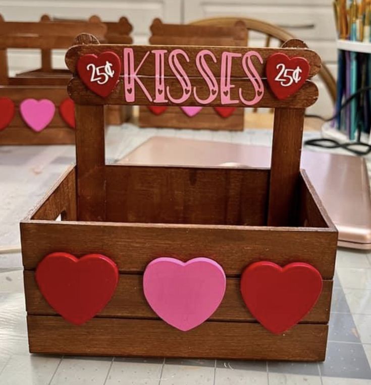 a wooden box with hearts on it and the word kiss spelled in pink, red and pink