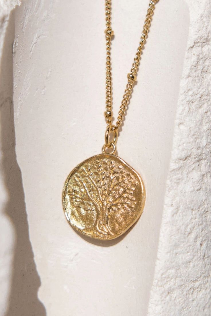 Inspiration : representing the tree of life - it symbolizes strength as a tree is the result of years of slow, patient growth. 24K sustainable gold plated pendant and chain (gilding : satin) Water resistant No risk of allergy (nickel-free, lead-free) Delivered in a vegan leather pouch with its gift box Length : 40 cm (15.7") + 10 cm extender (3.9") - diameter : 16 mm Ethically made in France Gold Tree Of Life Nature-inspired Jewelry, Symbolic Gold Jewelry With Tree Of Life, Nature-inspired Engraved Gold Necklace, Nature-inspired Nickel Free Gold Necklace, Engraved Gold Nature-inspired Necklace, The Tree Of Life, Leather Pouch, Modern Fashion, Tree Of Life