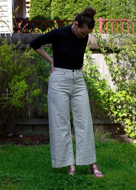 a woman is standing in the grass with her hands on her hips and looking down