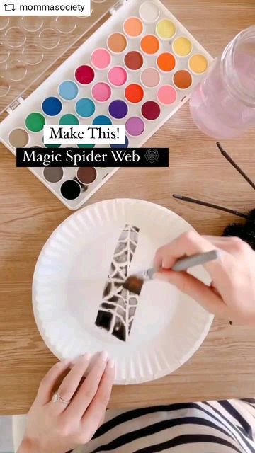 a woman is painting the eiffel tower on a paper plate with watercolors