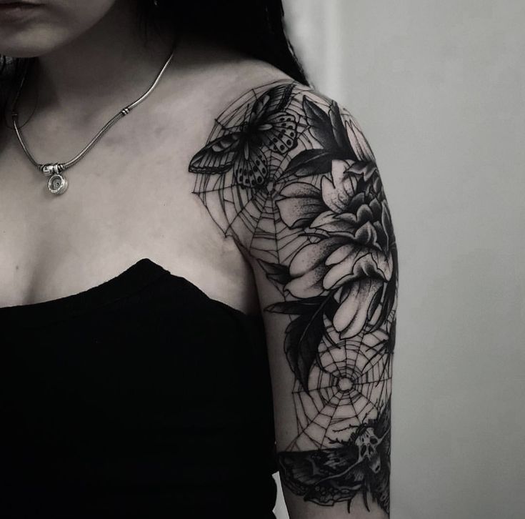 a woman wearing a black dress with flowers on her arm and chest tattooing it