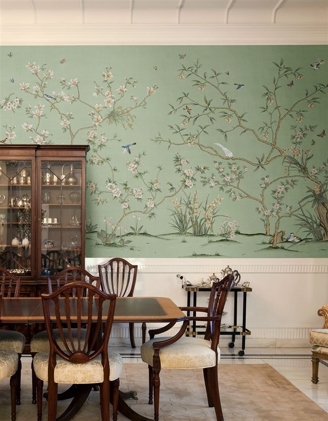 a dining room table with chairs and a china cabinet in front of a floral wallpaper