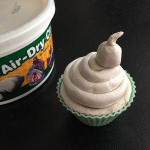 a cupcake sitting next to a container of air dry clay on top of a table