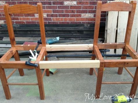 two wooden chairs sitting next to each other in front of a brick wall with tools on them