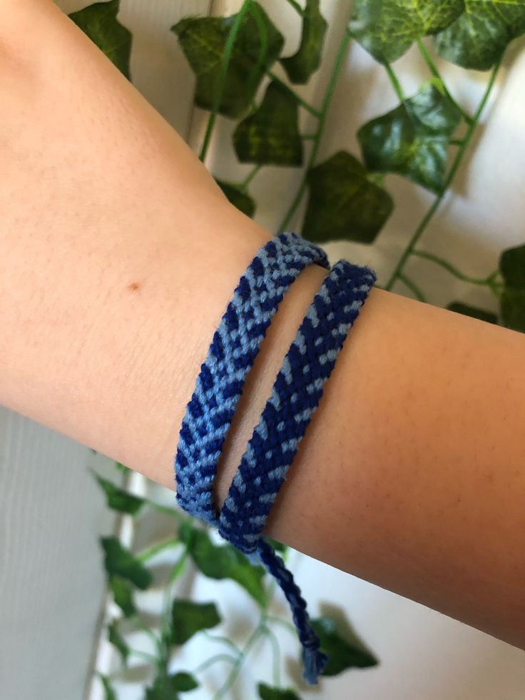 a woman's arm wearing a blue and white bracelet with two rows of braiding on it