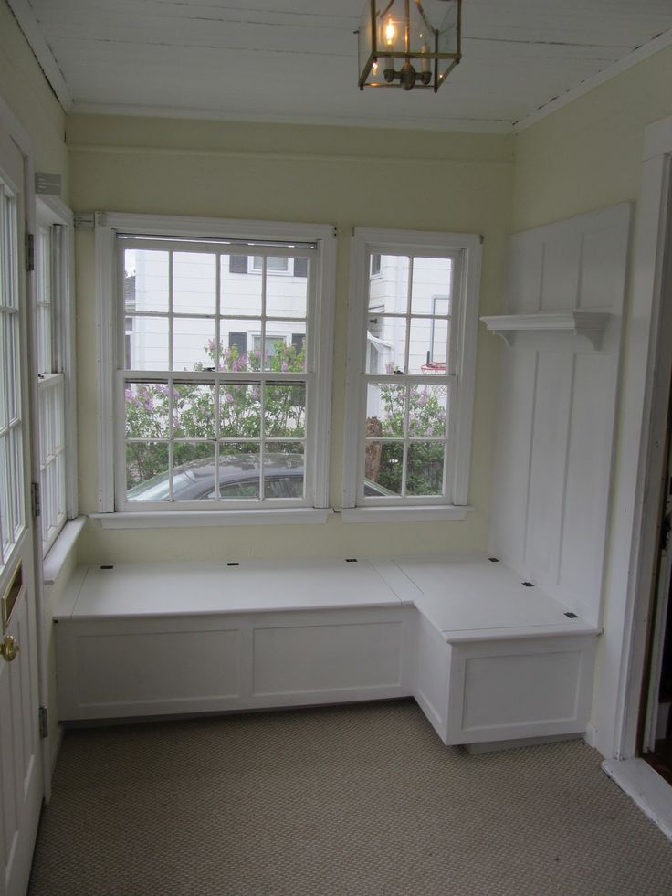 an empty room with two windows and a bench in the corner by the window sill