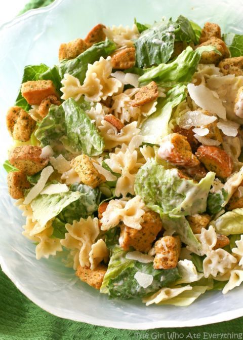 a salad with chicken, lettuce and croutons in it on a white plate