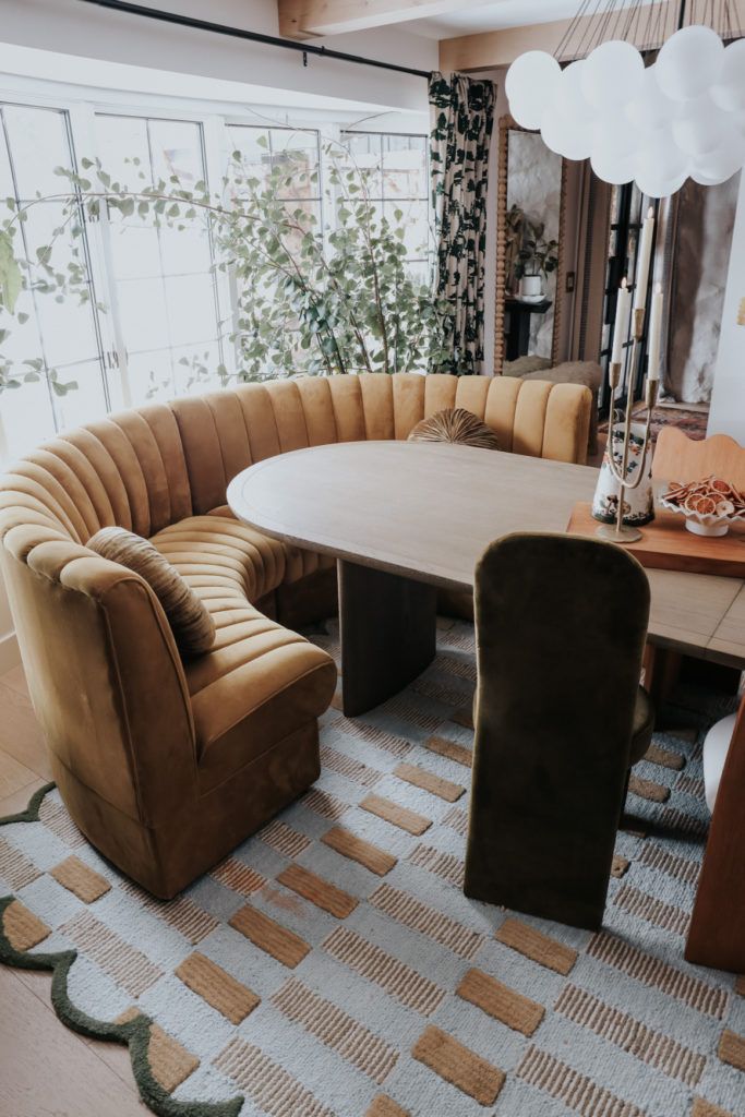 a large circular table surrounded by chairs in a room with windows and rugs on the floor