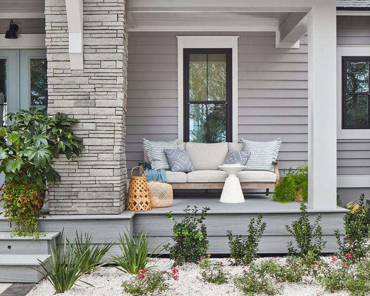 a couch sitting on top of a porch next to a planter filled with flowers