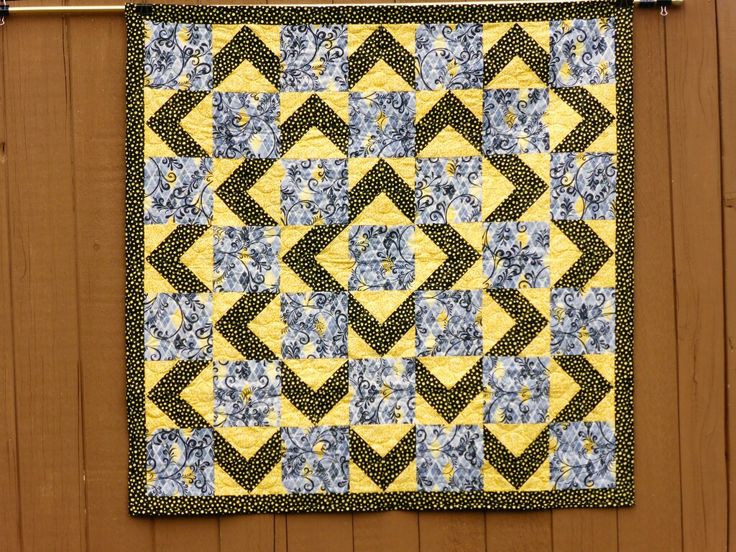 a yellow and blue quilt hanging on a wooden wall