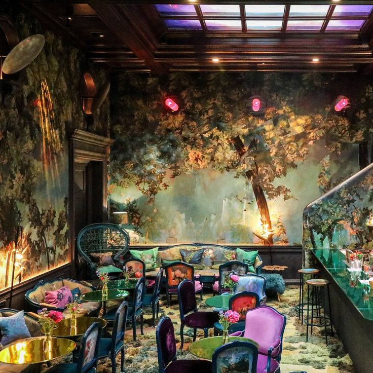 the interior of a fancy restaurant with colorful chairs and walls covered in wallpapers