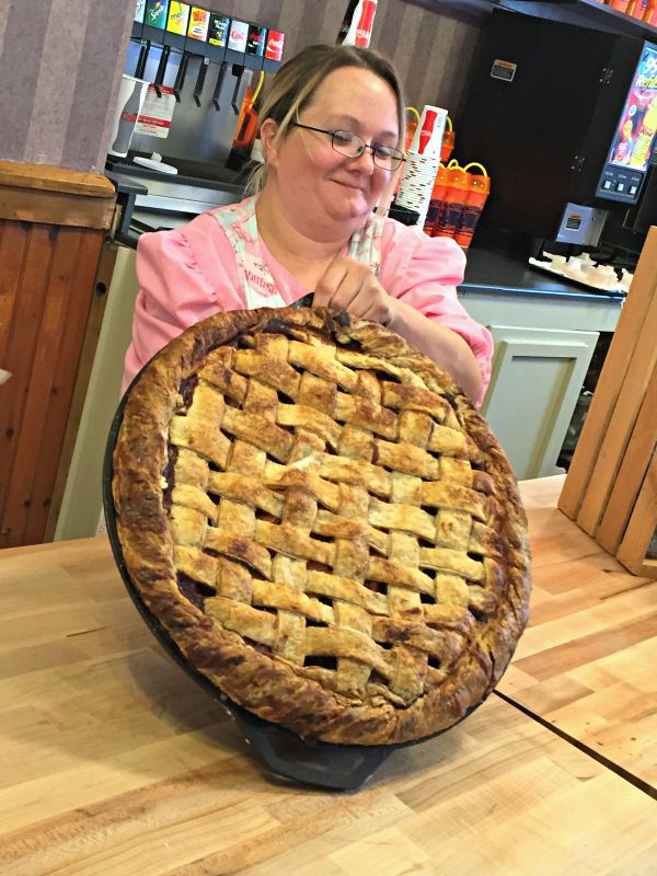 a woman sitting at a table with a pie in front of her on the counter