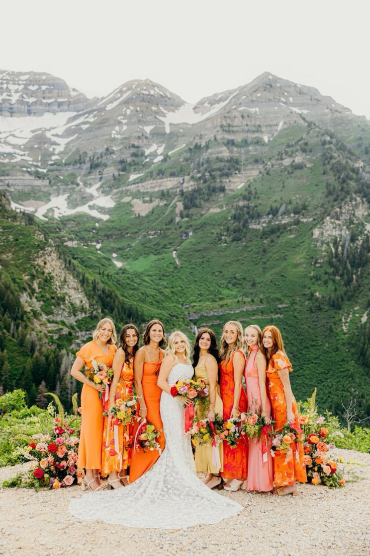 a group of women standing next to each other on top of a mountain with mountains in the background