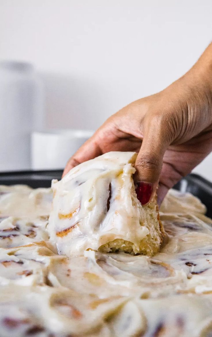 someone is dipping some kind of food into the batter on top of it's pan