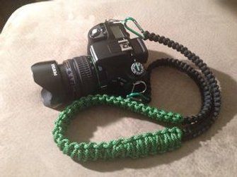 a camera with a green lanyard attached to it's body on a bed