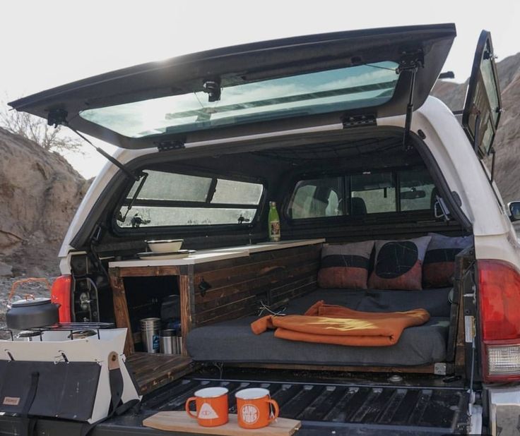 the back end of a truck with its trunk open and camping gear in the bed