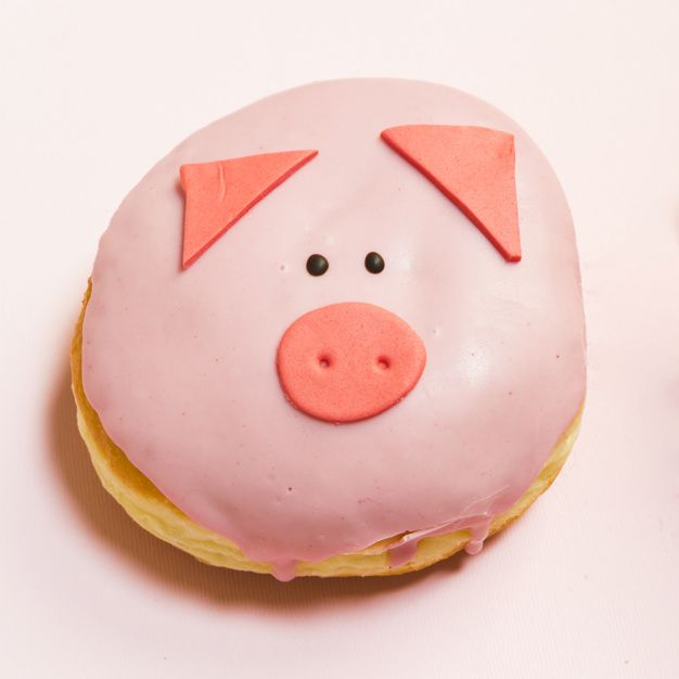 a pink frosted doughnut with a pig face on it