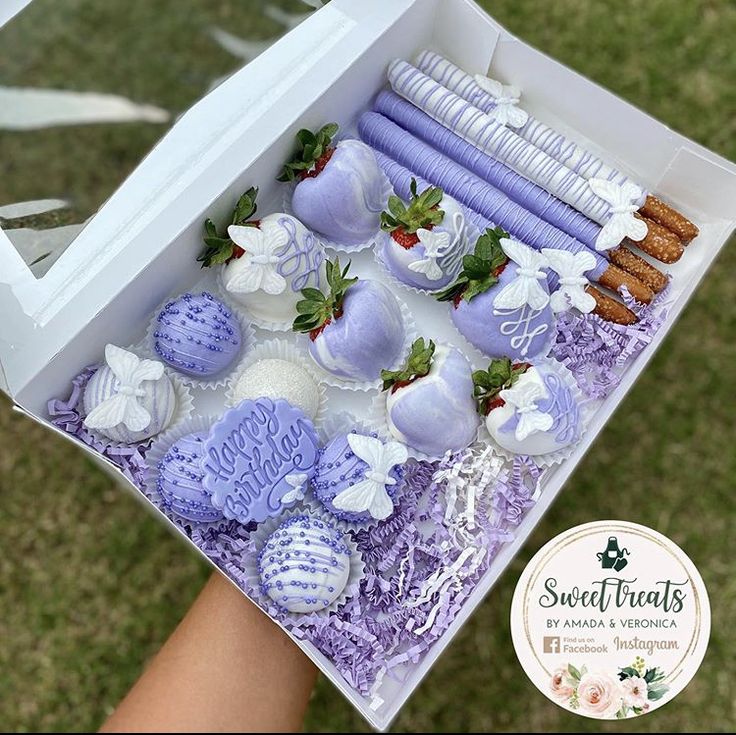 a box filled with purple and white desserts on top of a grass covered field