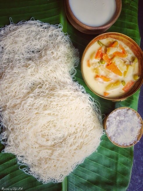 some food is laying out on a banana leaf with other foods in bowls around it