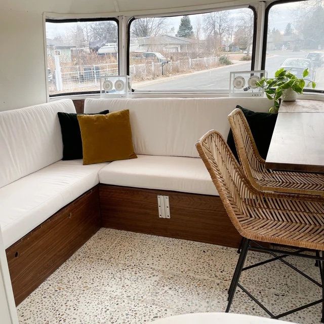 the inside of a camper with white couches and wicker chairs in it