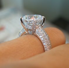 a close up of a person's hand with a diamond ring on their finger