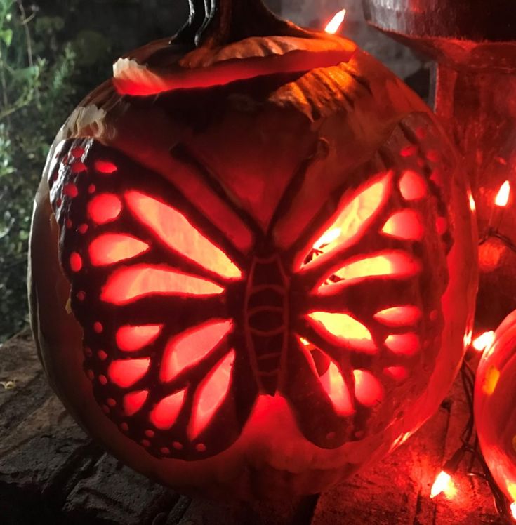 a carved pumpkin with a butterfly on it's side and some lights around it