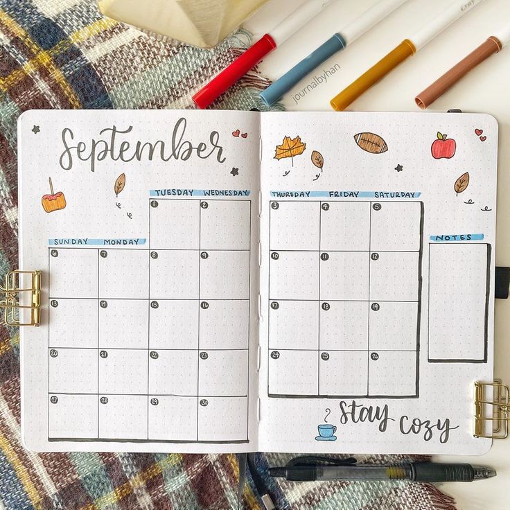 an open planner with autumn stickers on it next to some markers and pencils