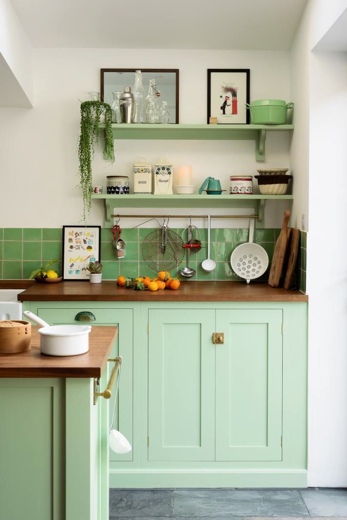 a kitchen with green cabinets and wooden counter tops in the center is filled with food items