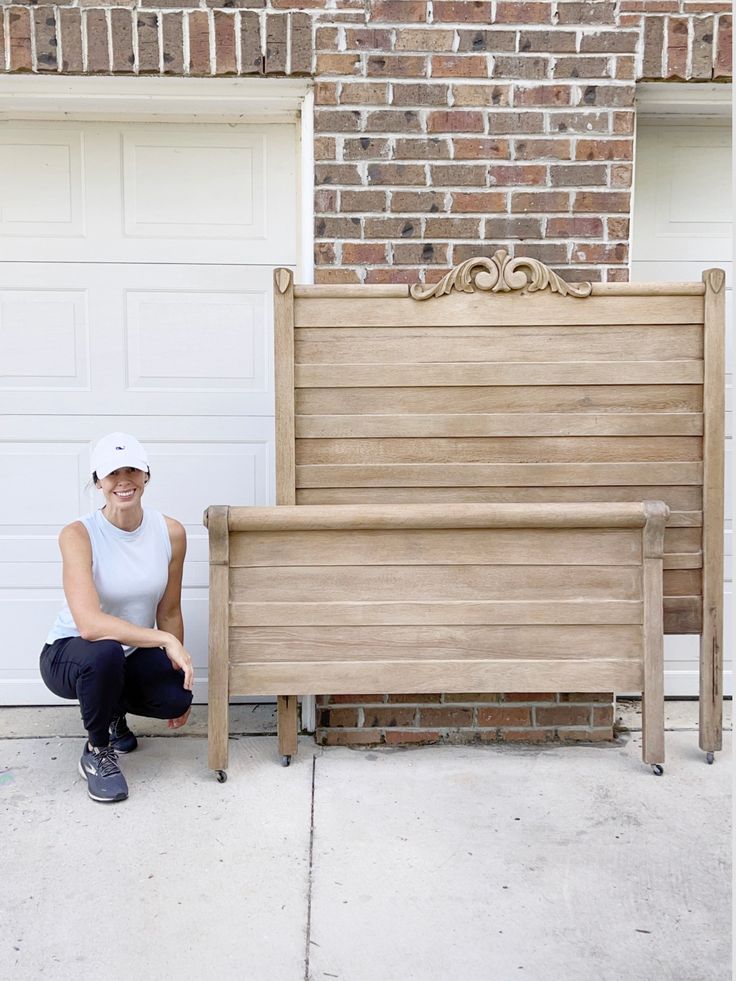 a woman sitting on a bench in front of a garage door with a brick wall behind her