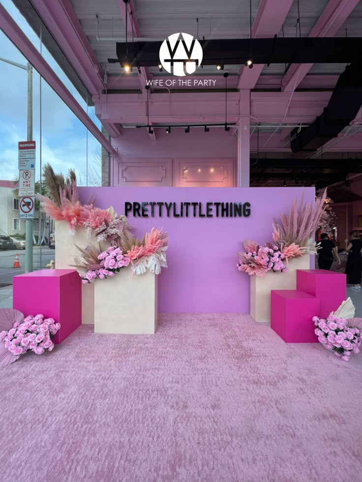 pink carpeted area with two boxes and flowers on the floor in front of a sign that says pretty little thing