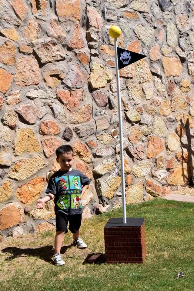 a young boy standing in front of a flag pole with a yellow ball on it