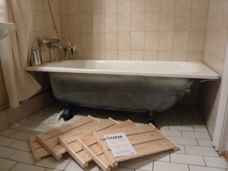 a bath tub sitting next to a pile of wooden planks on the floor in a bathroom