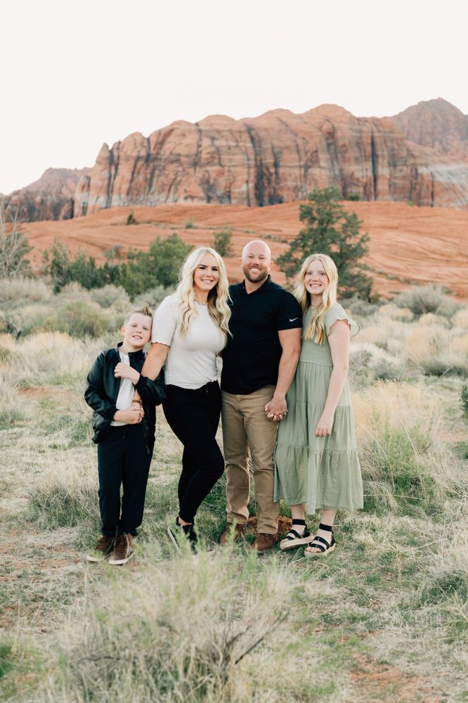 a family posing for a photo in front of the red rock formations at sunset with mountains in the background