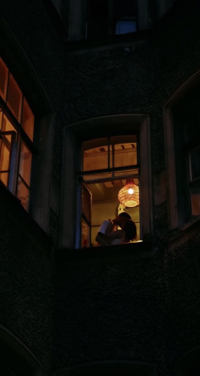 two people standing in an open window at night