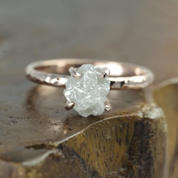 a white diamond ring sitting on top of a piece of wood