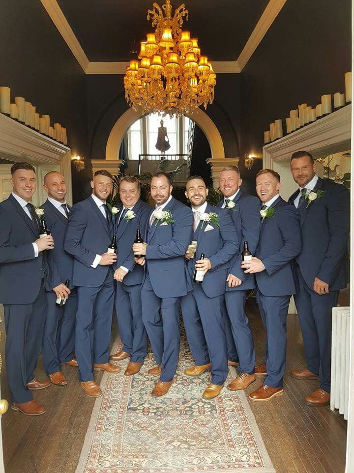 a group of men standing next to each other in front of a chandelier