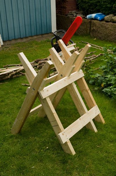 a wooden chair sitting in the grass next to a garden tool holder with tools on it