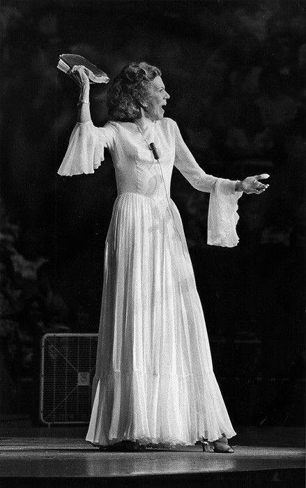 an old black and white photo of a woman in a long dress with her arms outstretched