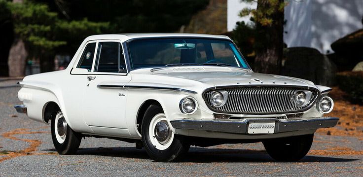 an old white car is parked on the street