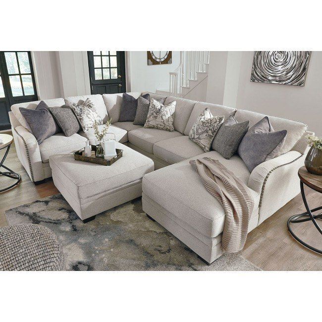 a living room filled with lots of furniture and pillows on top of a wooden floor