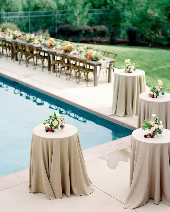 an outdoor dining area with tables and chairs next to a swimming pool covered in tablecloths