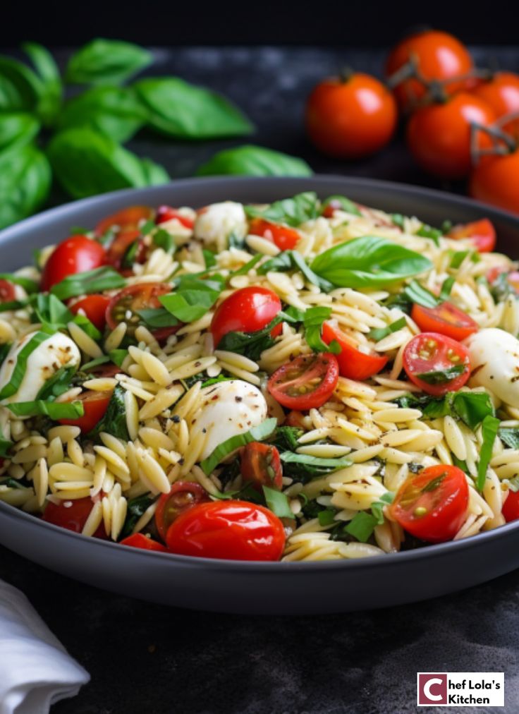 a bowl full of pasta with tomatoes, basil and mozzarella on the side