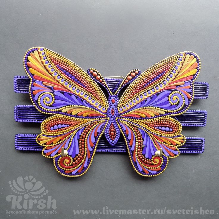 a purple and orange butterfly hair clip on a gray surface with the words, livemaster