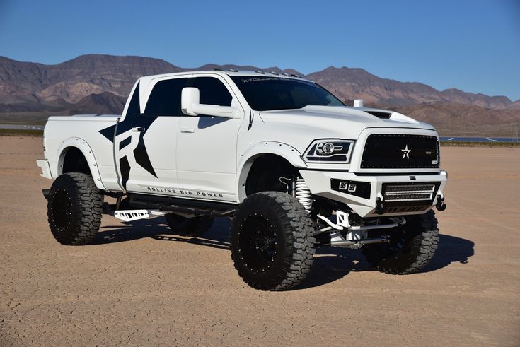 a large white truck parked on top of a dirt field