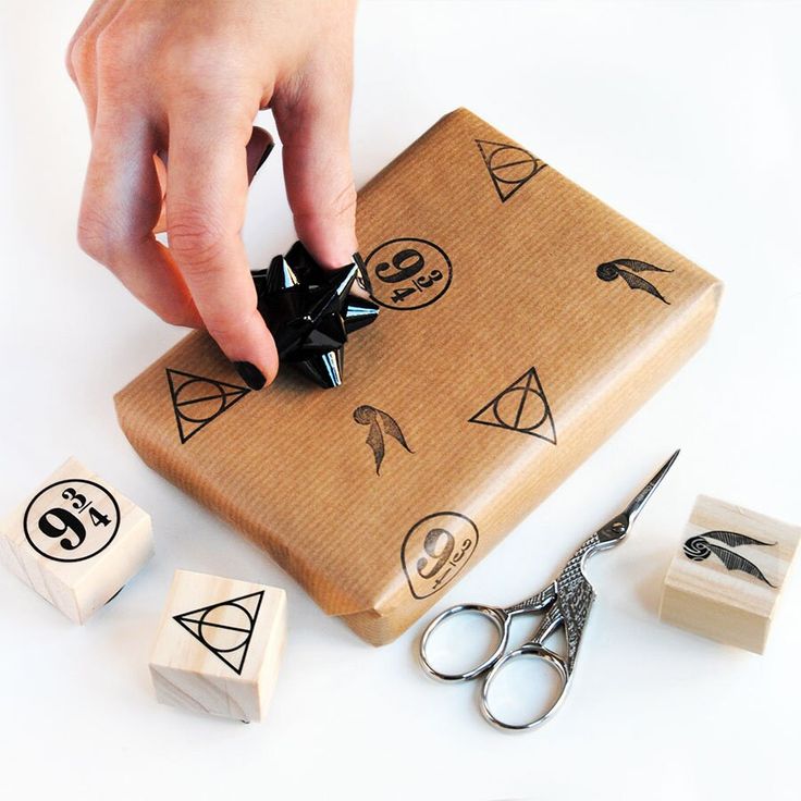 a person's hand on top of a box with scissors and other items around it