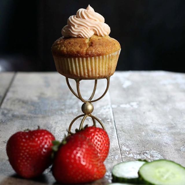 there is a cupcake and two strawberries on the table with cucumbers