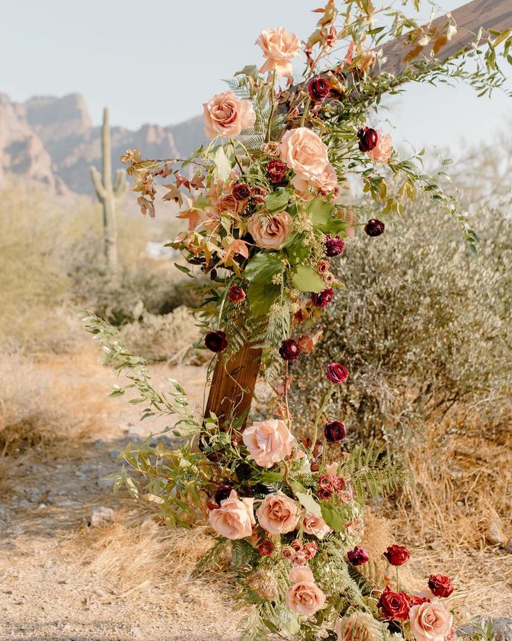 an outdoor wedding arch with flowers and greenery in the desert, surrounded by cacti