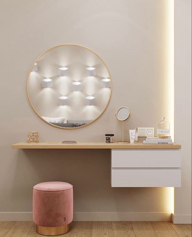 a vanity with a round mirror and stool in front of it, along with a pink ottoman