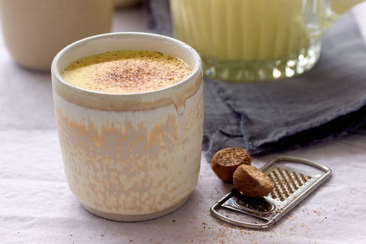 a cup of hot chocolate next to a cookie on a napkin and a grater