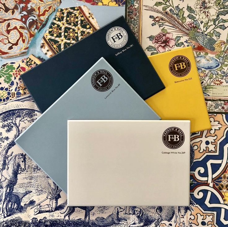 three different colored envelopes sitting next to each other on top of a patterned table cloth